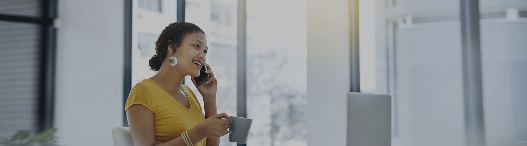 Woman on phone sitting at desk with coffee
